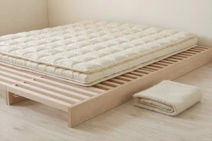 A quilted mattress pad resting on a slatted wooden base
